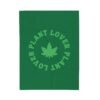 This plant lover weed leaf blanket features a bold weed leaf design with 'Plant Lover' written around it, all in a green color same as the weed leaf itself. Weed Leaf blanket is green